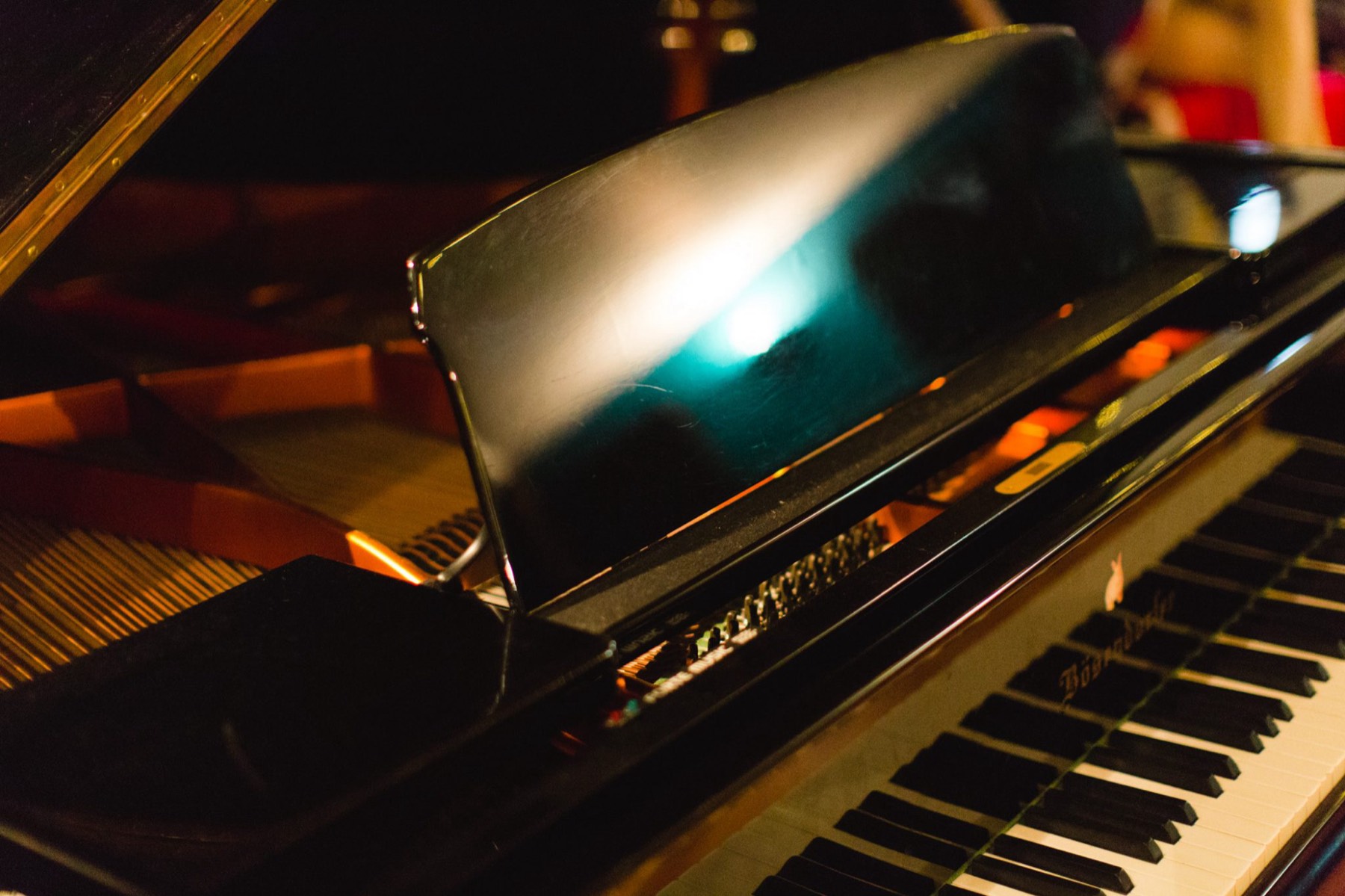 The music desk and keys of the Bösendorfer grand, lit by a single lamp