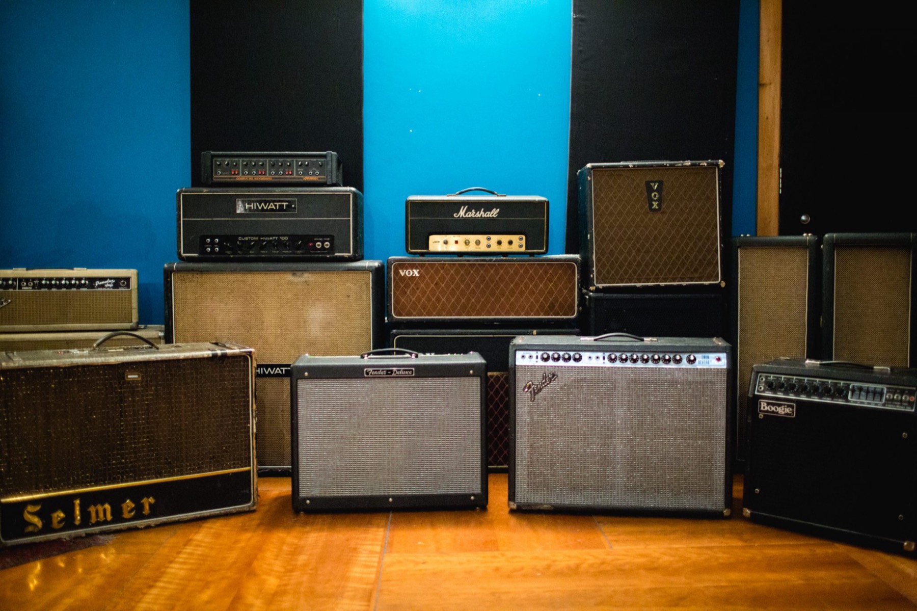 A wall of vintage amps against a blue studio wall